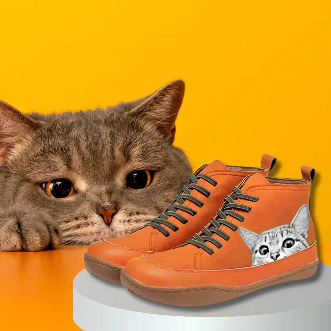 Women's cat print high-top shoes in orange next to a cat
