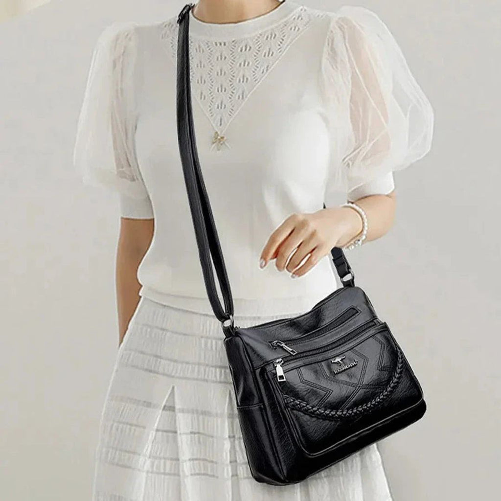 Women's leather look crossbody bag with zip pockets in black, worn crossbody