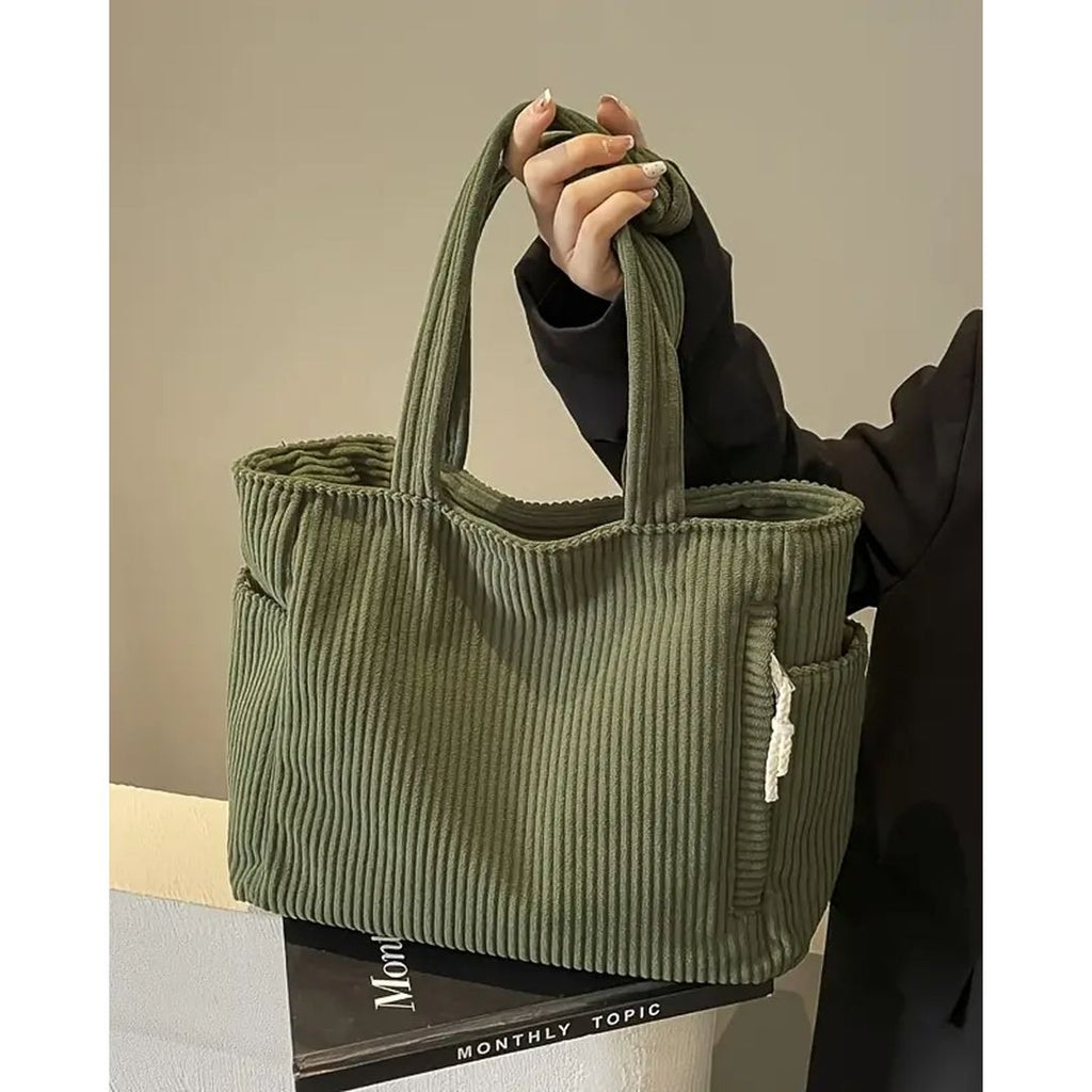 Women's ribbed tote bag with side pockets in olive green, carried by hand