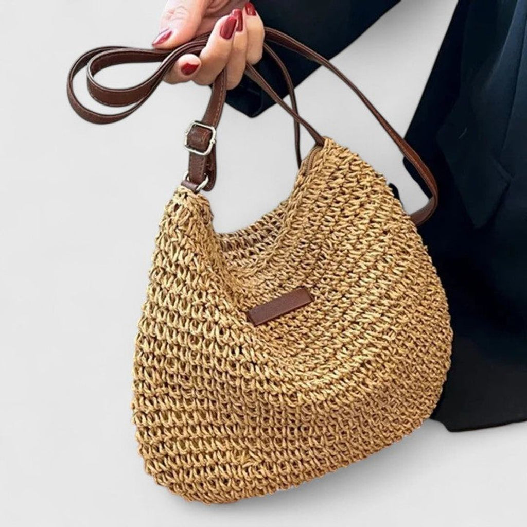 Women's woven half moon shoulder bag in tan, held in hand
